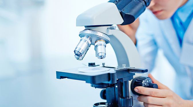 technician looking through microscope