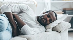 man laying on couch holding stomach